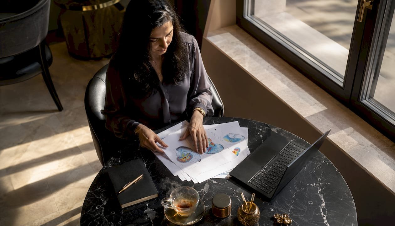 O femeie aranjează materiale despre sănătatea creierului la birou, pregătindu-se să le folosească pentru activități de wellness mental.