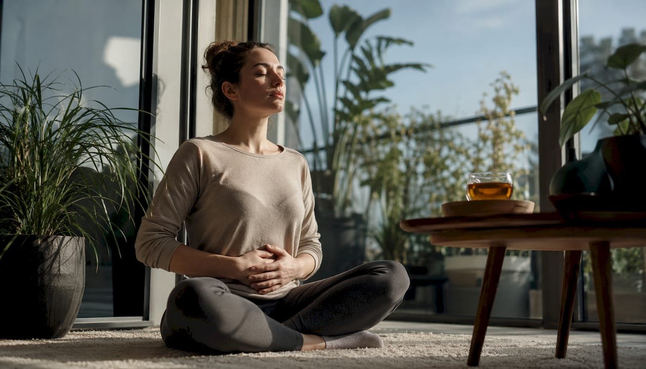 O femeie exersează respirația abdominală în confortul propriei case
